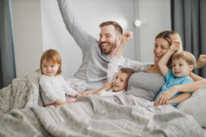 ベッドで家族で手を挙げて喜んでいる写真