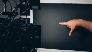 黒い背景とカメラと指示を出す男性の手の画像