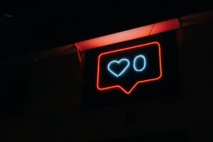 真夜中の壁にあるいいねマークが電気で光ってる画像