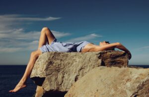 岩の上でのんびりと過ごしているサングラスをかけた女性の画像